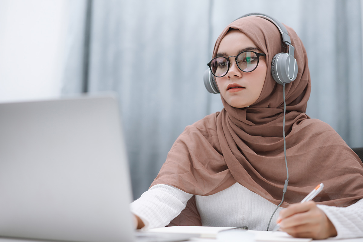 Young woman listening to ESL ebook content on a laptop - ELT and e-learning audio production