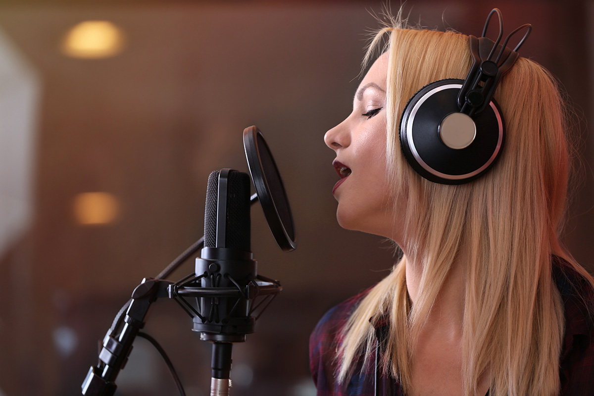 Woman singing into a microphone recording jingles - Jingle and music production